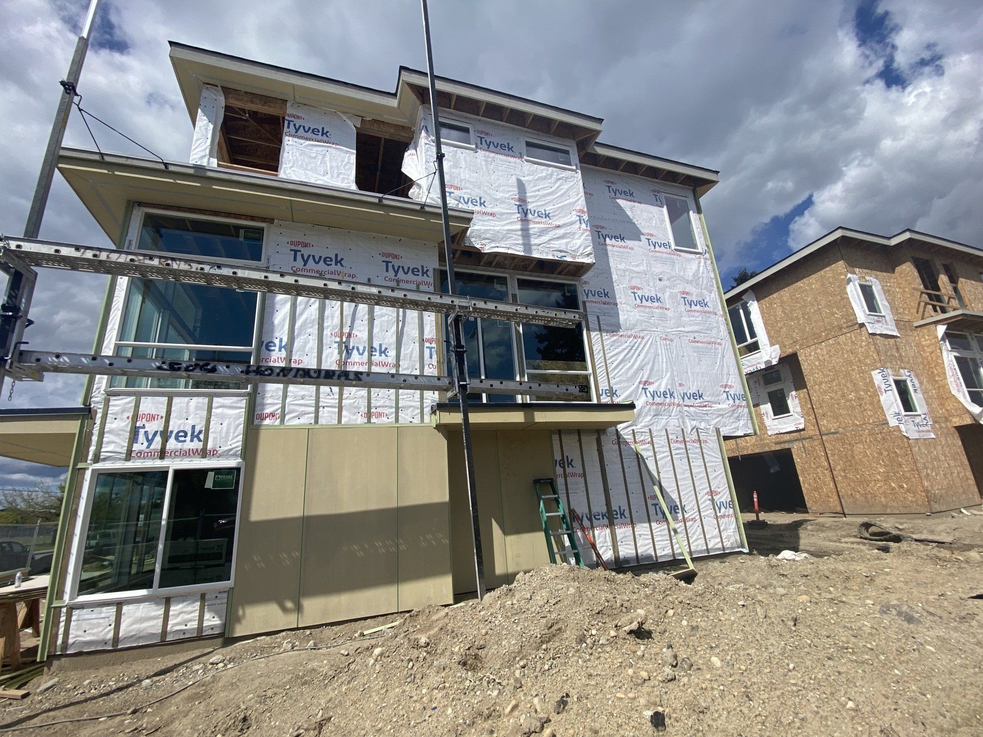 A large house is being built on top of a dirt hill.