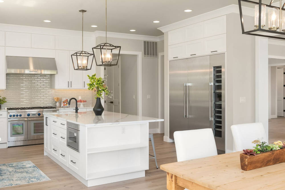 A kitchen with white cabinets and stainless steel appliances and a wooden table.