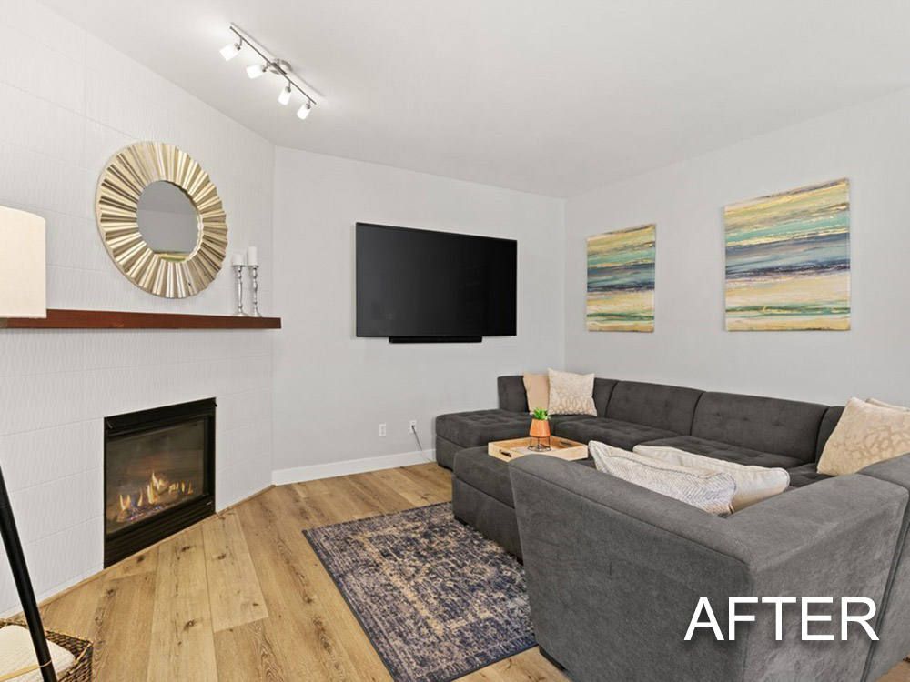 A living room with a couch , fireplace , television and mirror.