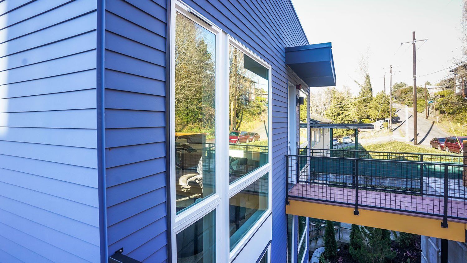 A blue house with a balcony and a lot of windows.