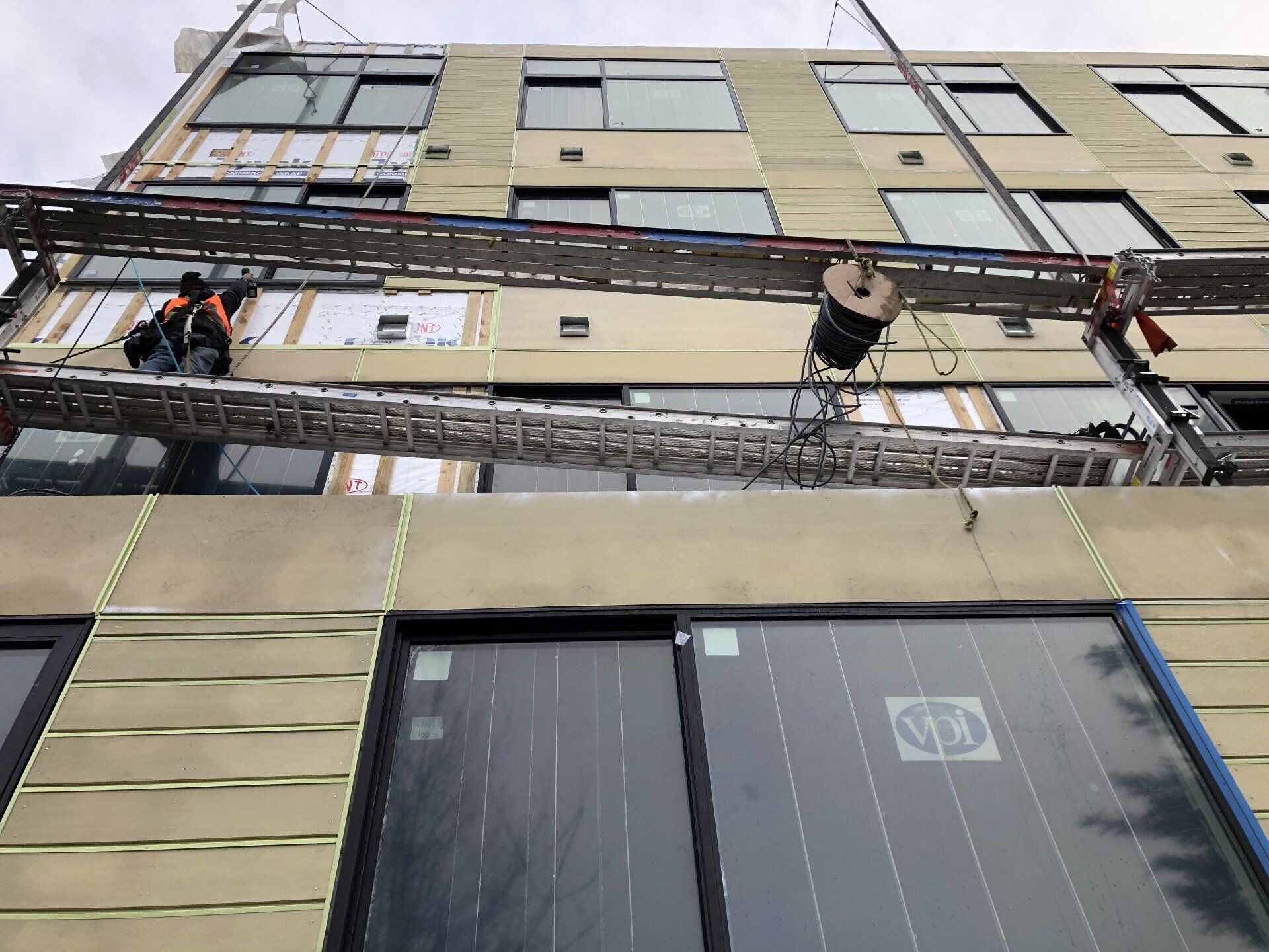 A man is sitting on a ladder on the side of a building.