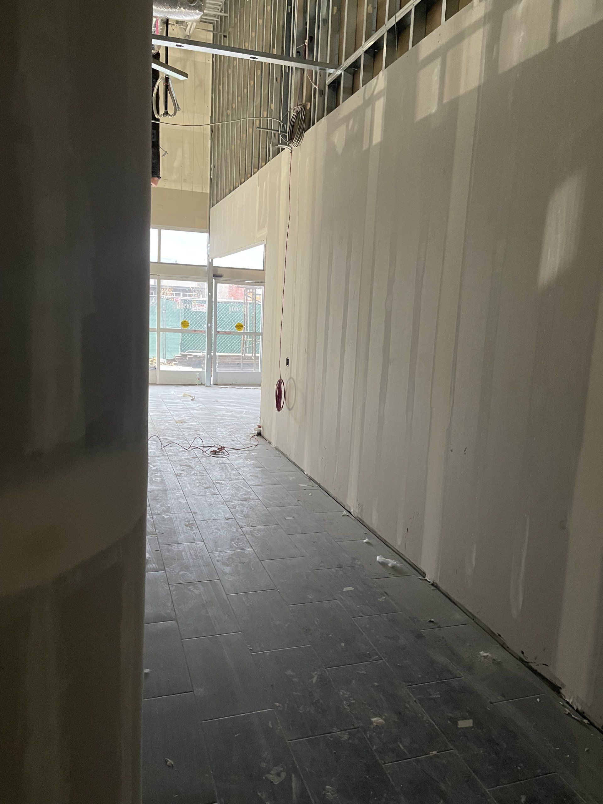 A hallway in a building under construction with a fire extinguisher on the wall.