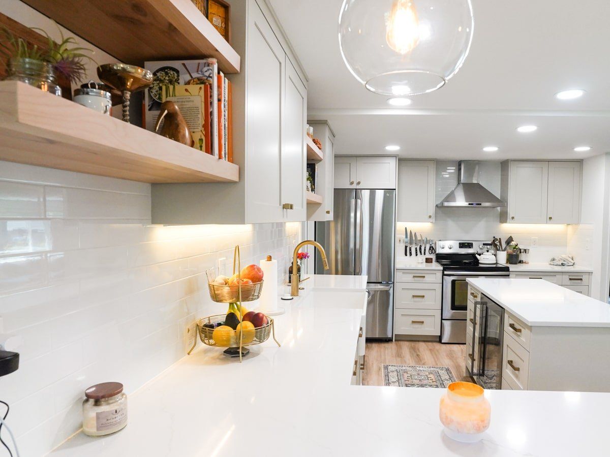 A kitchen with white cabinets and stainless steel appliances and a fruit basket on the counter.