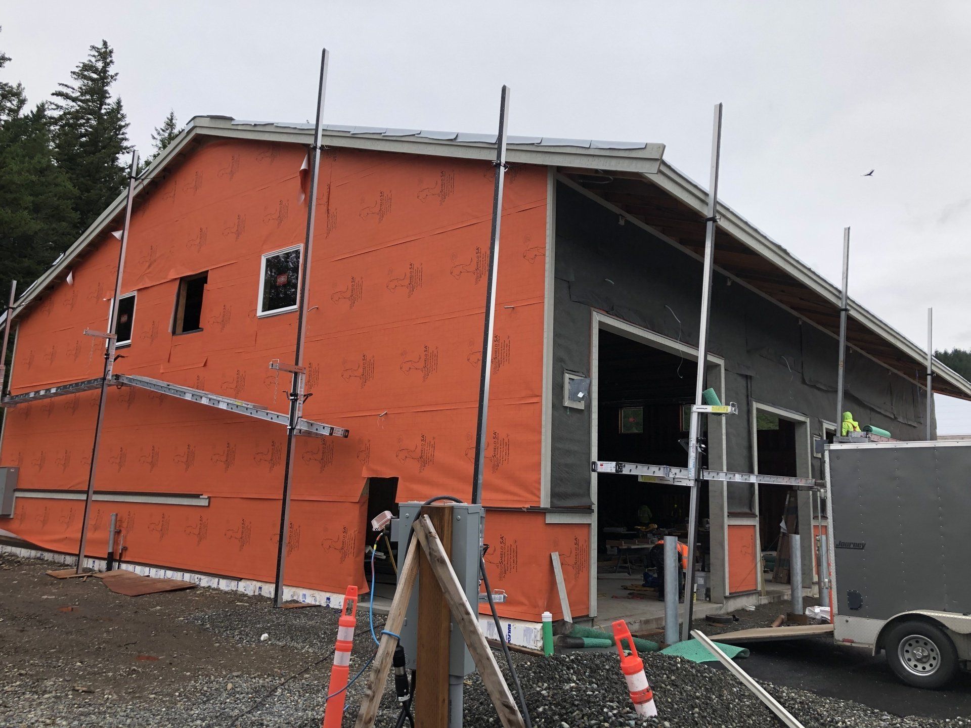 A building is being built with orange insulation and a truck is parked in front of it.