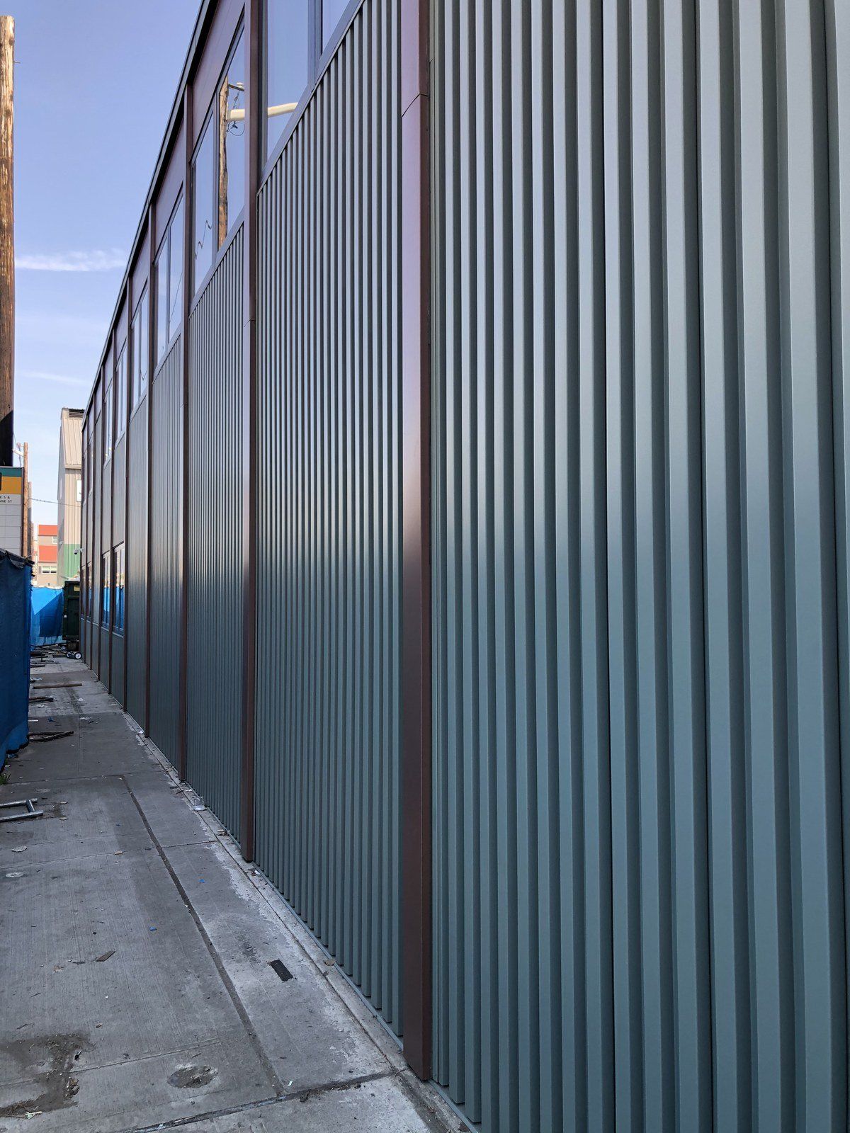 A large metal fence is surrounding a building under construction.