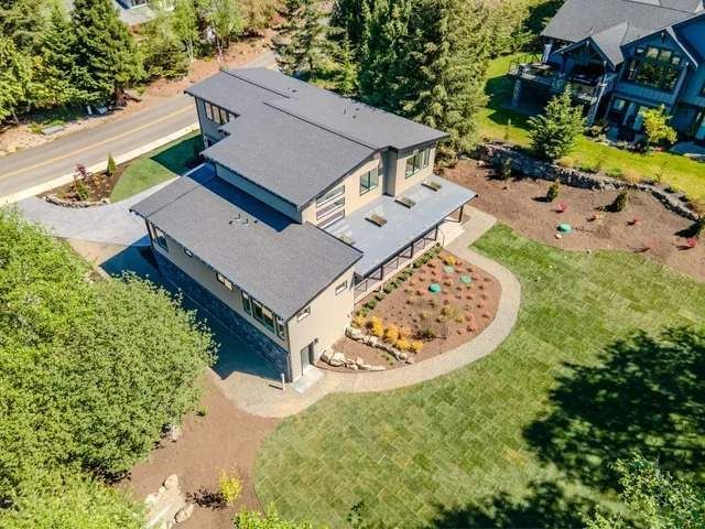 Aerial view of a modern gray house with a landscaped yard and curved garden beds.