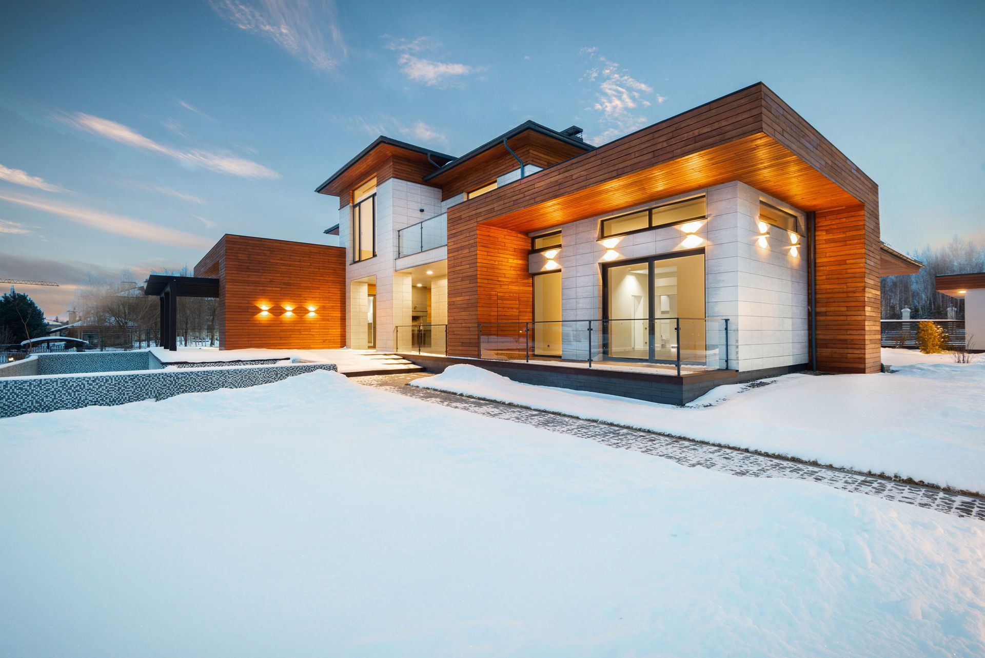 A modern house with a lot of windows is covered in snow.
