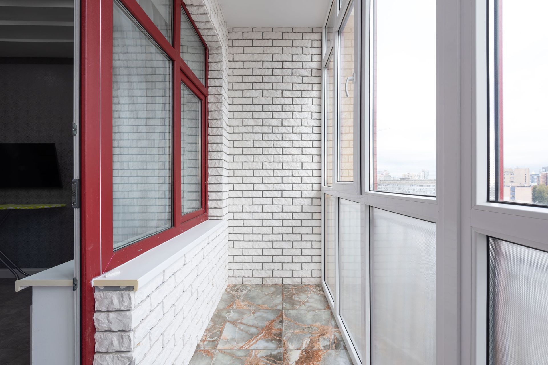 A balcony with a brick wall and a lot of windows.