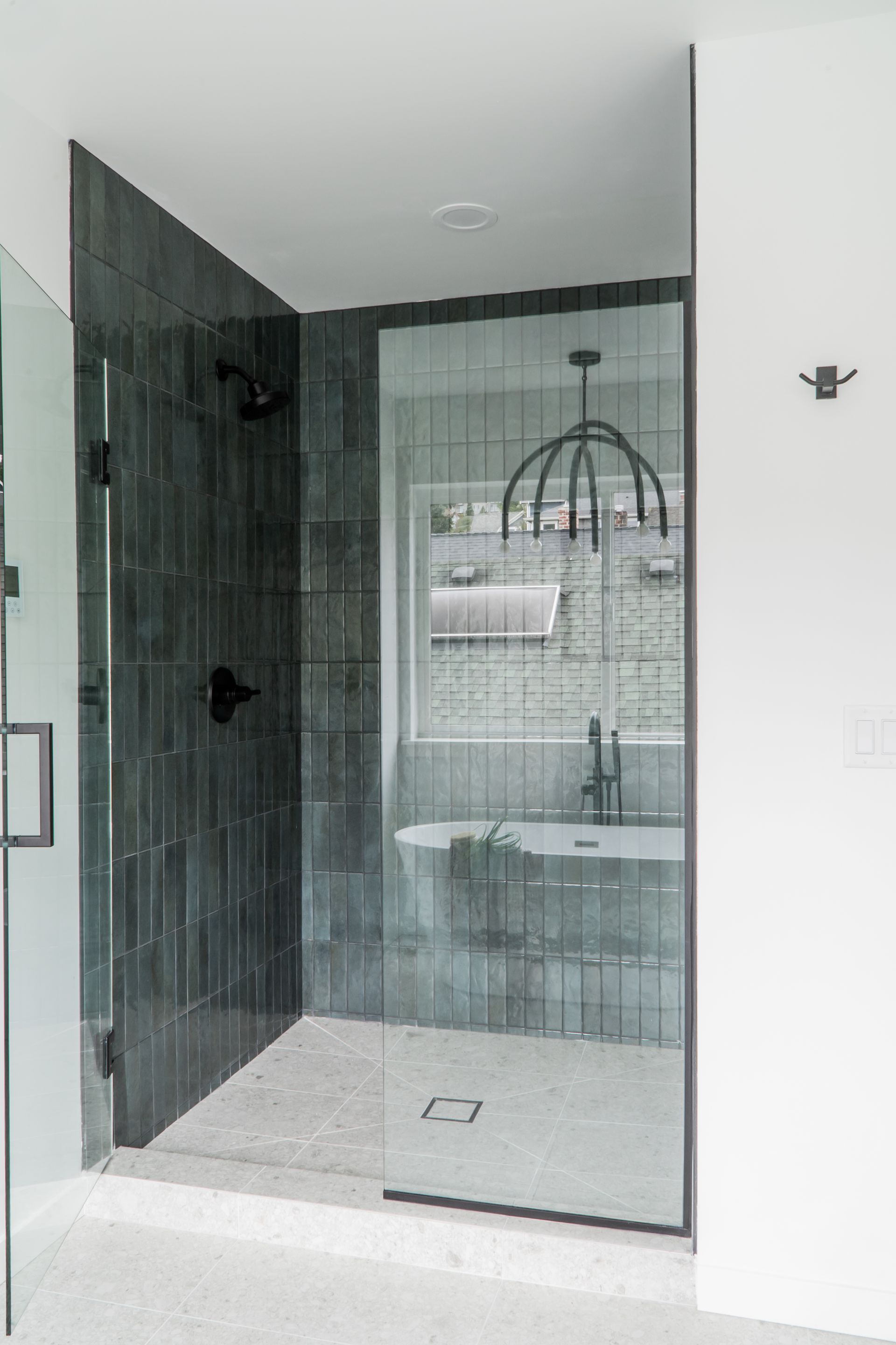 Modern bathroom shower with dark glass tiles, glass door, white vanity, and rainfall showerhead