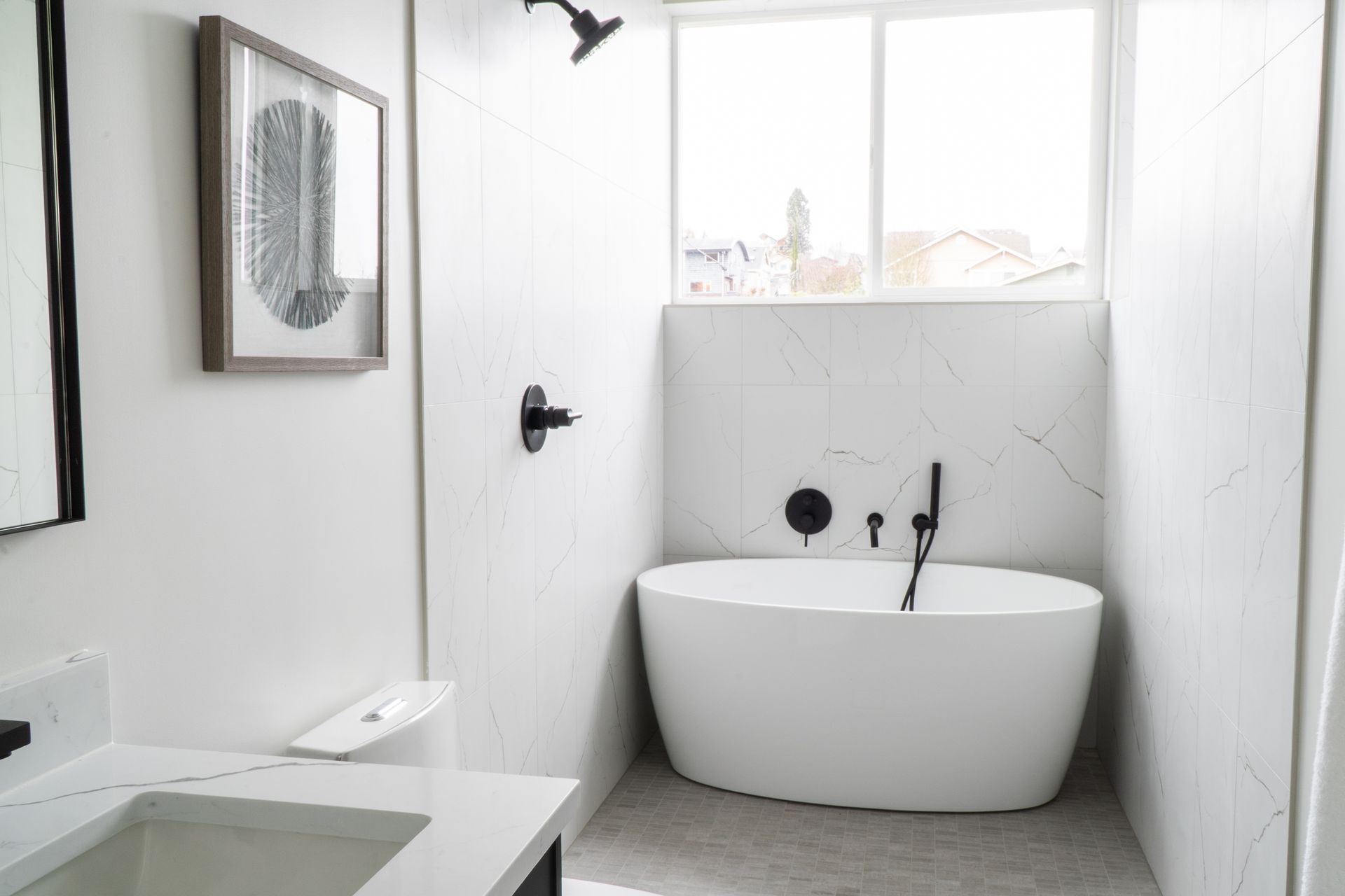 Modern white bathroom with freestanding tub, walk-in shower, and vanity sink