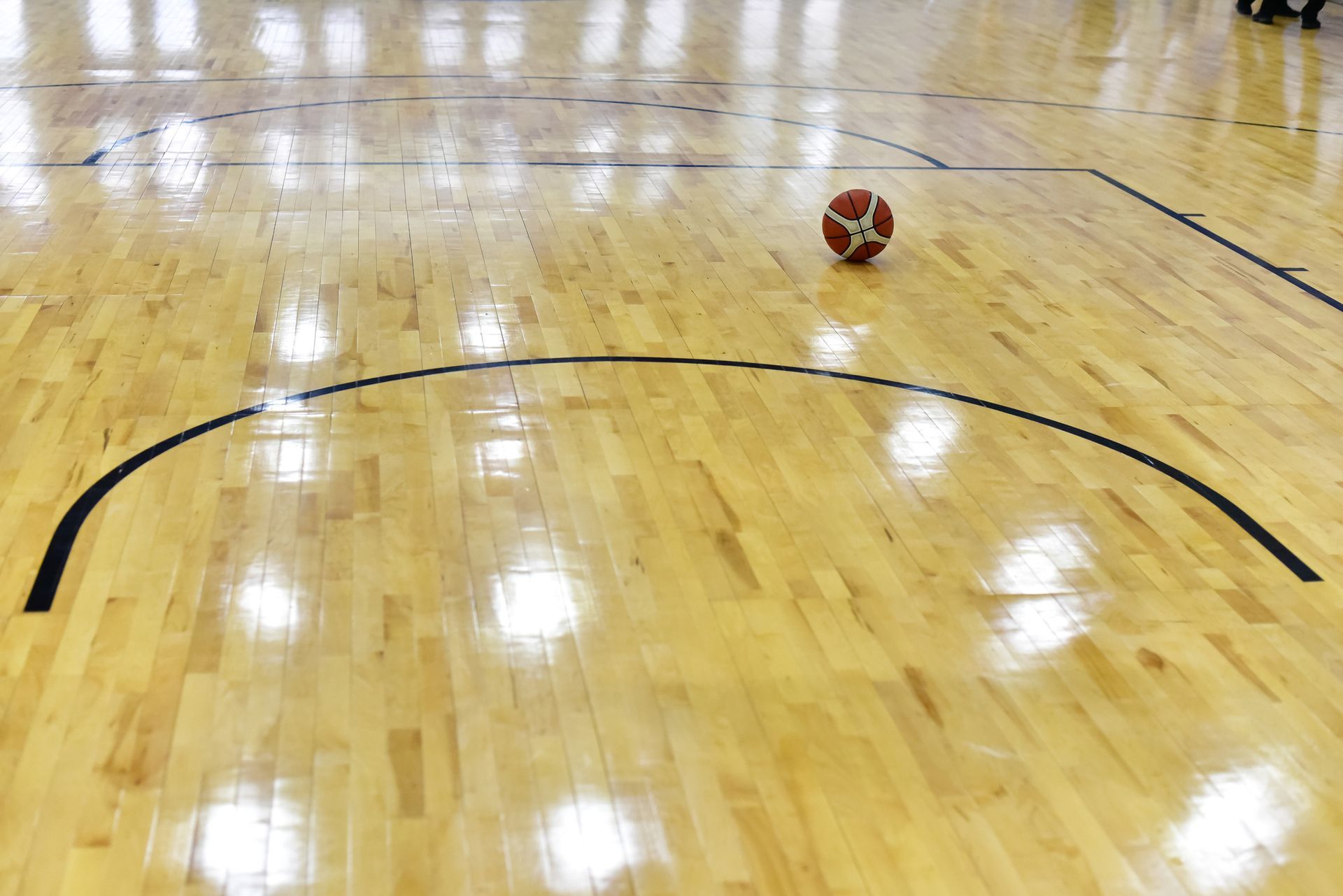 A basketball is on the floor of a basketball court.