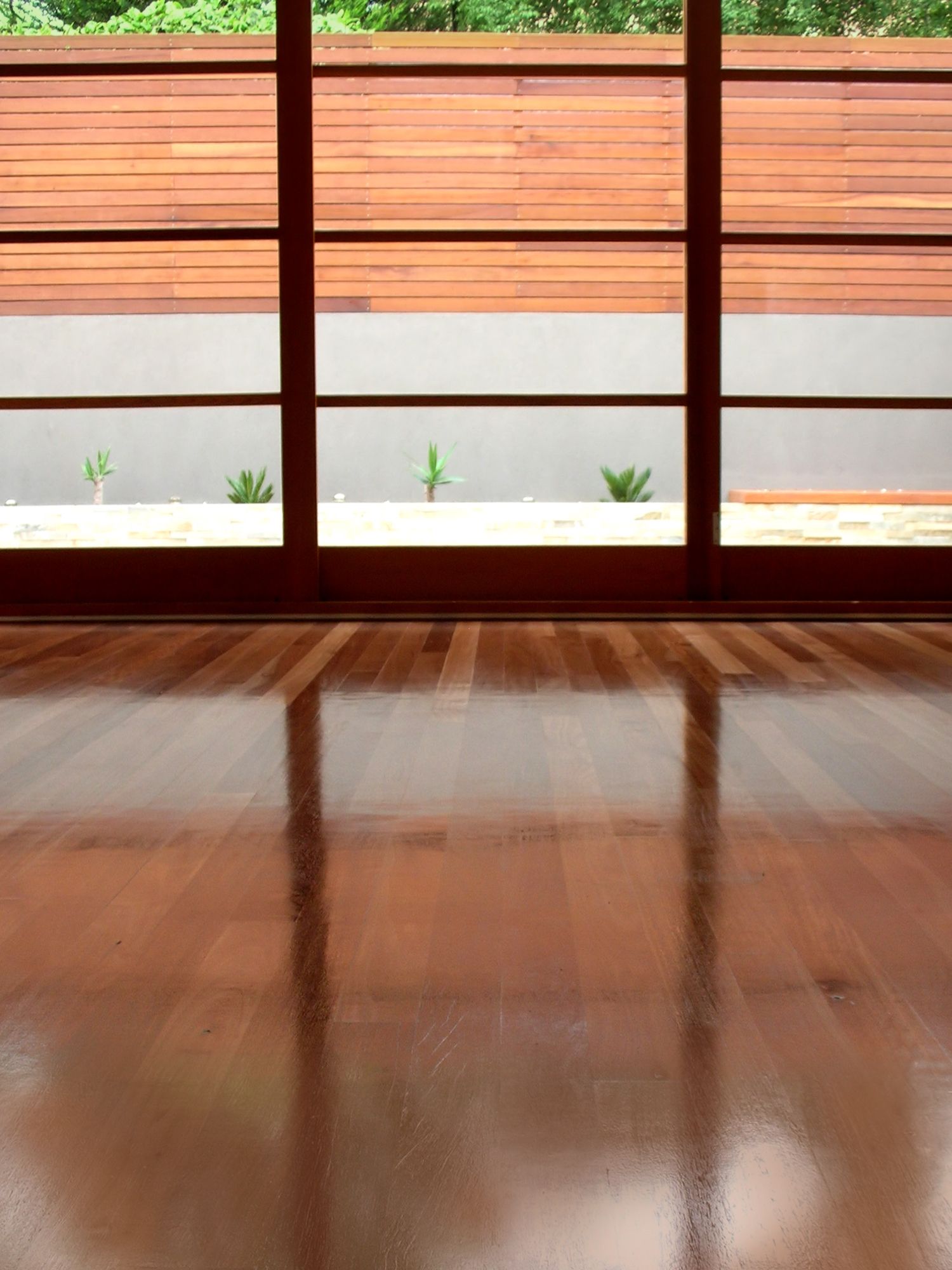 An empty room with a wooden floor and sliding glass doors.