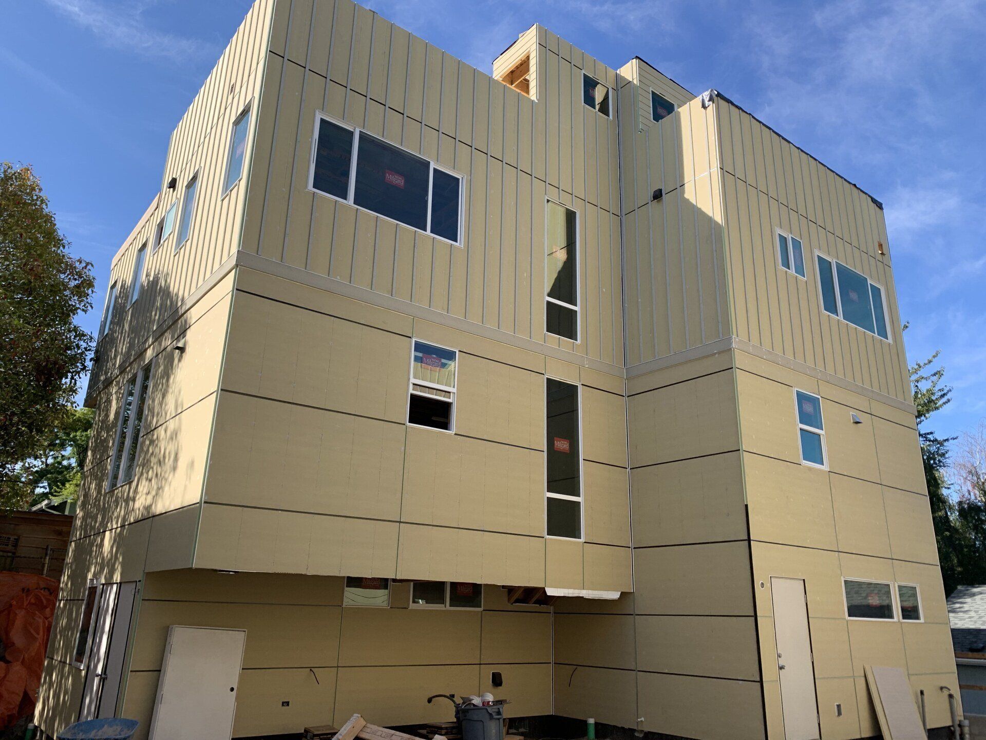 Modern beige multi-story building with geometric windows and a curved facade under a blue sky