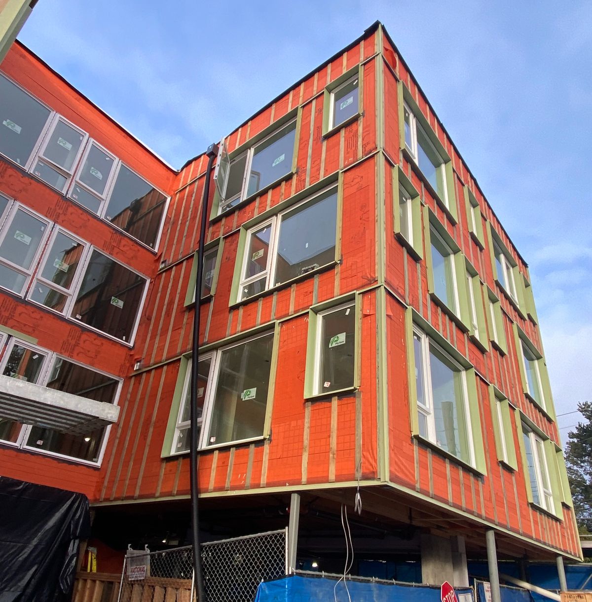 Modern red-and-black building exterior with many windows against a blue sky
