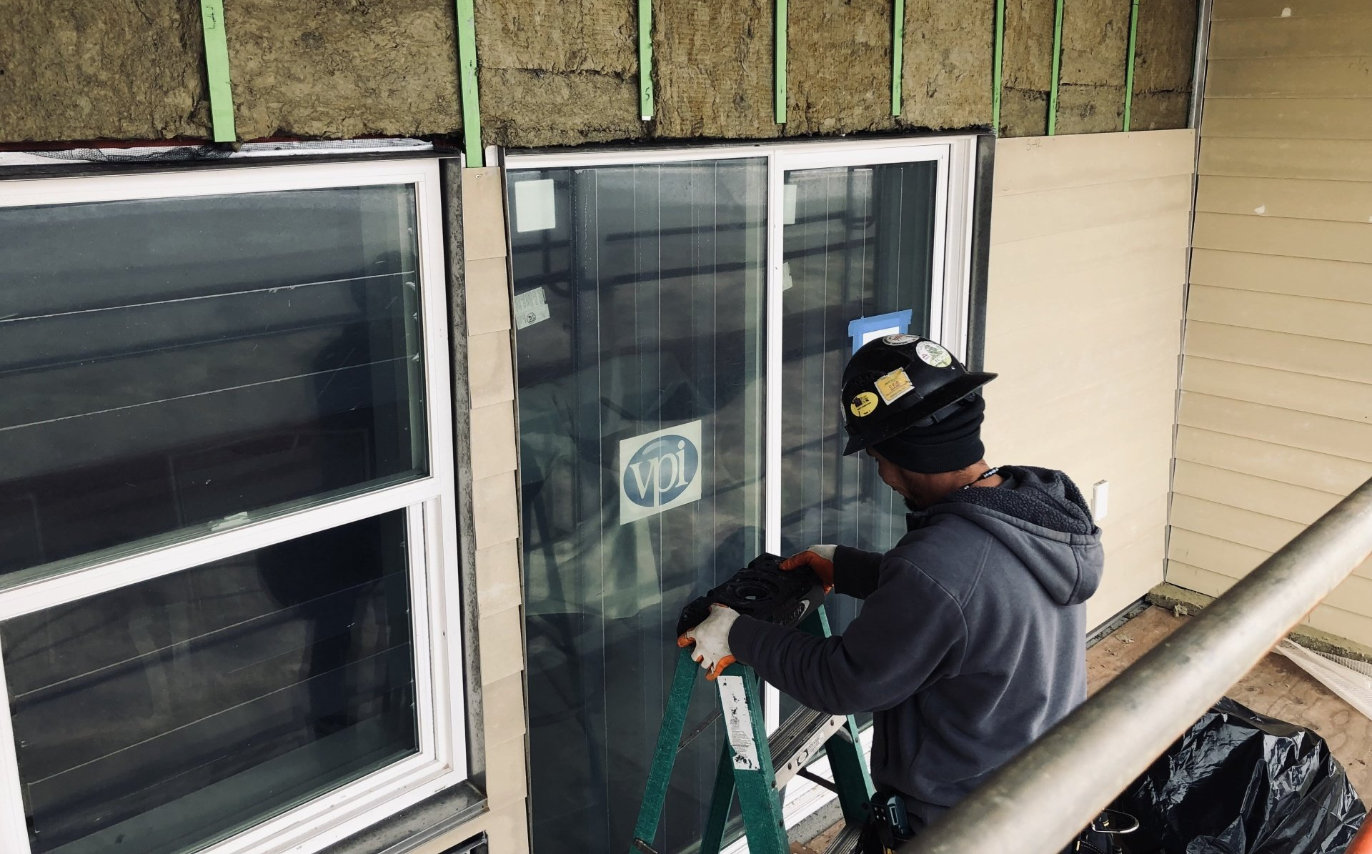 A man is standing on a ladder working on a window.