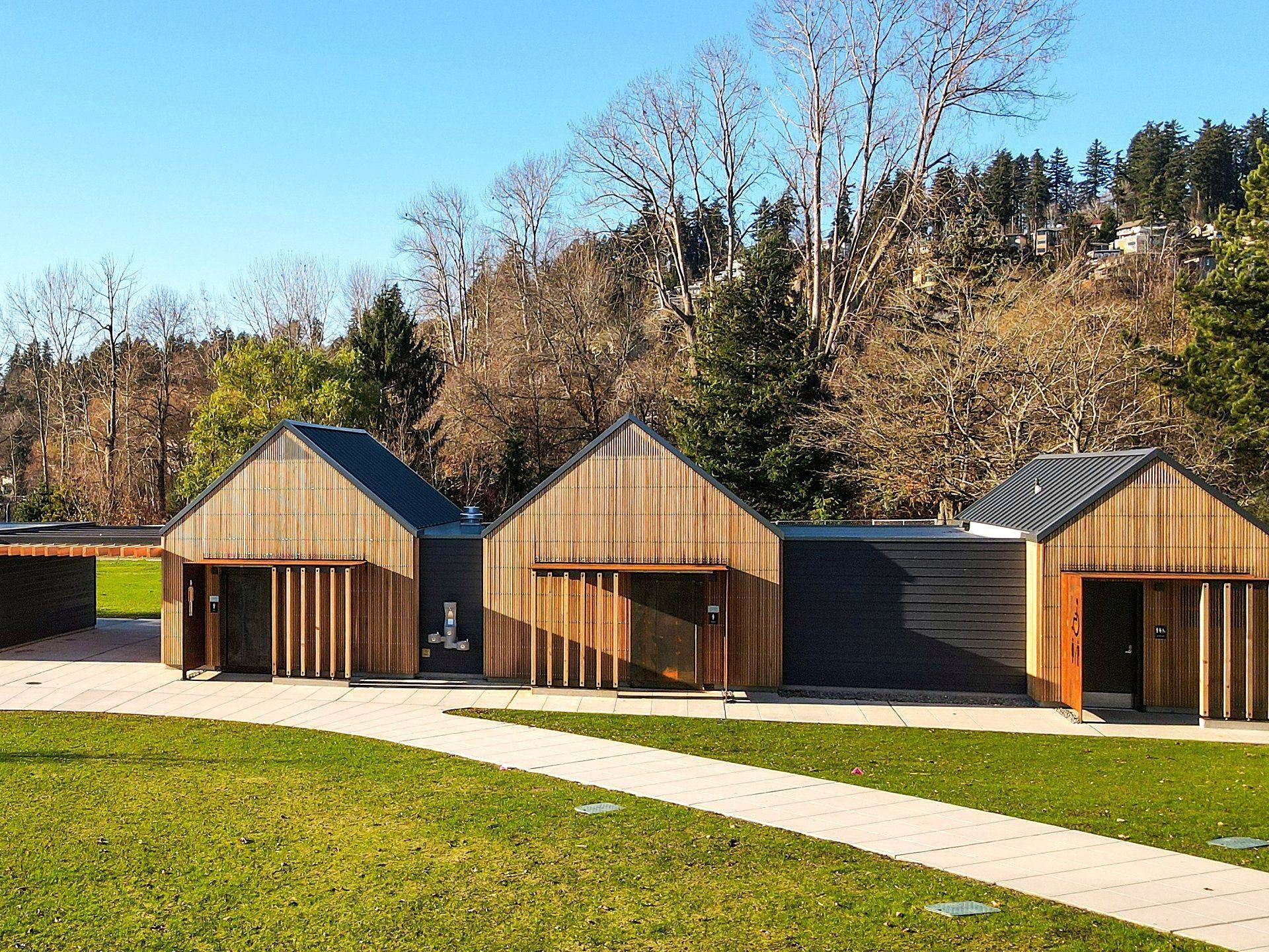 A row of wooden houses are sitting next to each other on a lush green field.