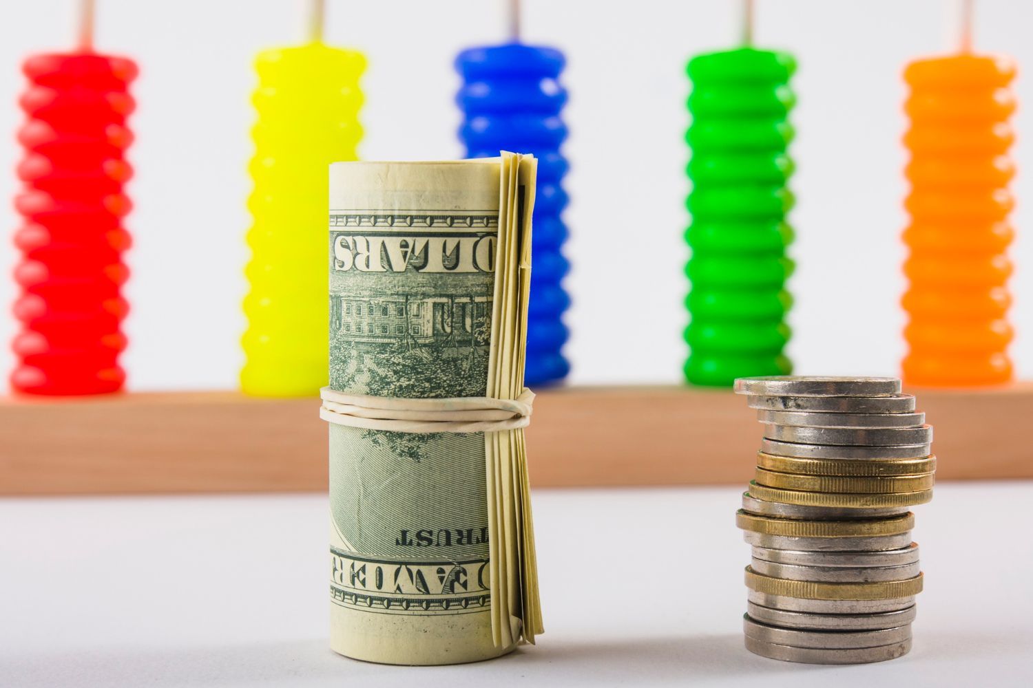 A roll of money is sitting next to a stack of coins.
