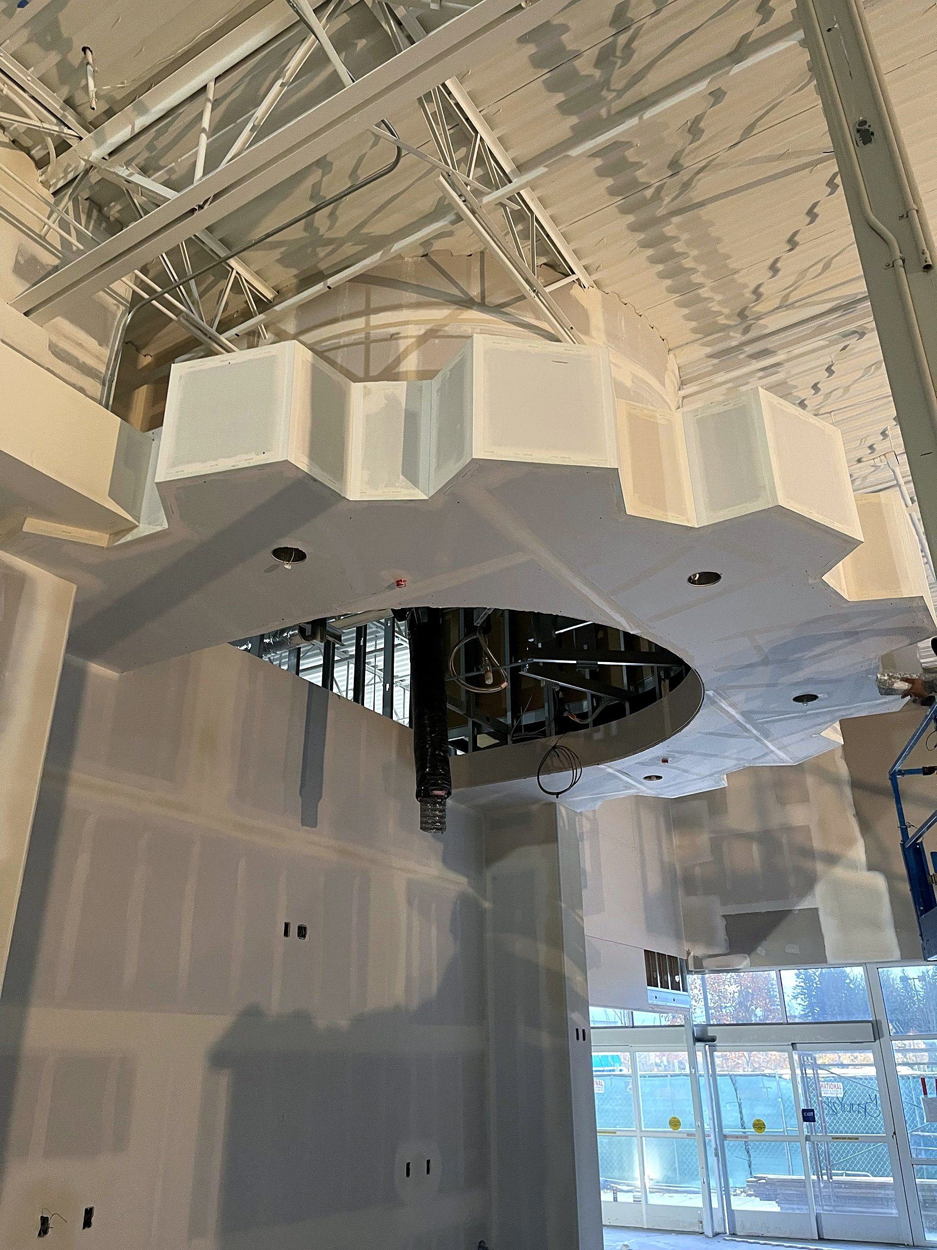 A cow is sitting in the middle of a large building under construction.