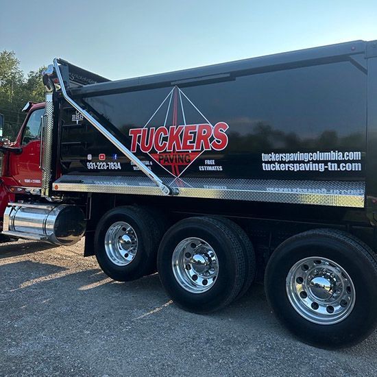 Black Tucker's landscaping dump truck parked outdoors on a sunny day