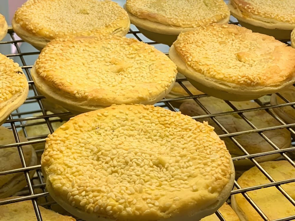 A Bunch Of Pies Are Sitting On A Cooling Rack — Cedar Park Bakehouse in Taranganba, QLD