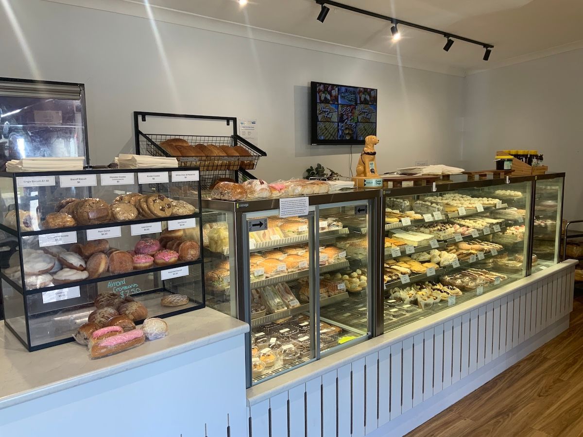 Bakery display cases filled with pastries and cakes in a bright shop interior — Cedar Park Bakehouse in Taranganba, QLD