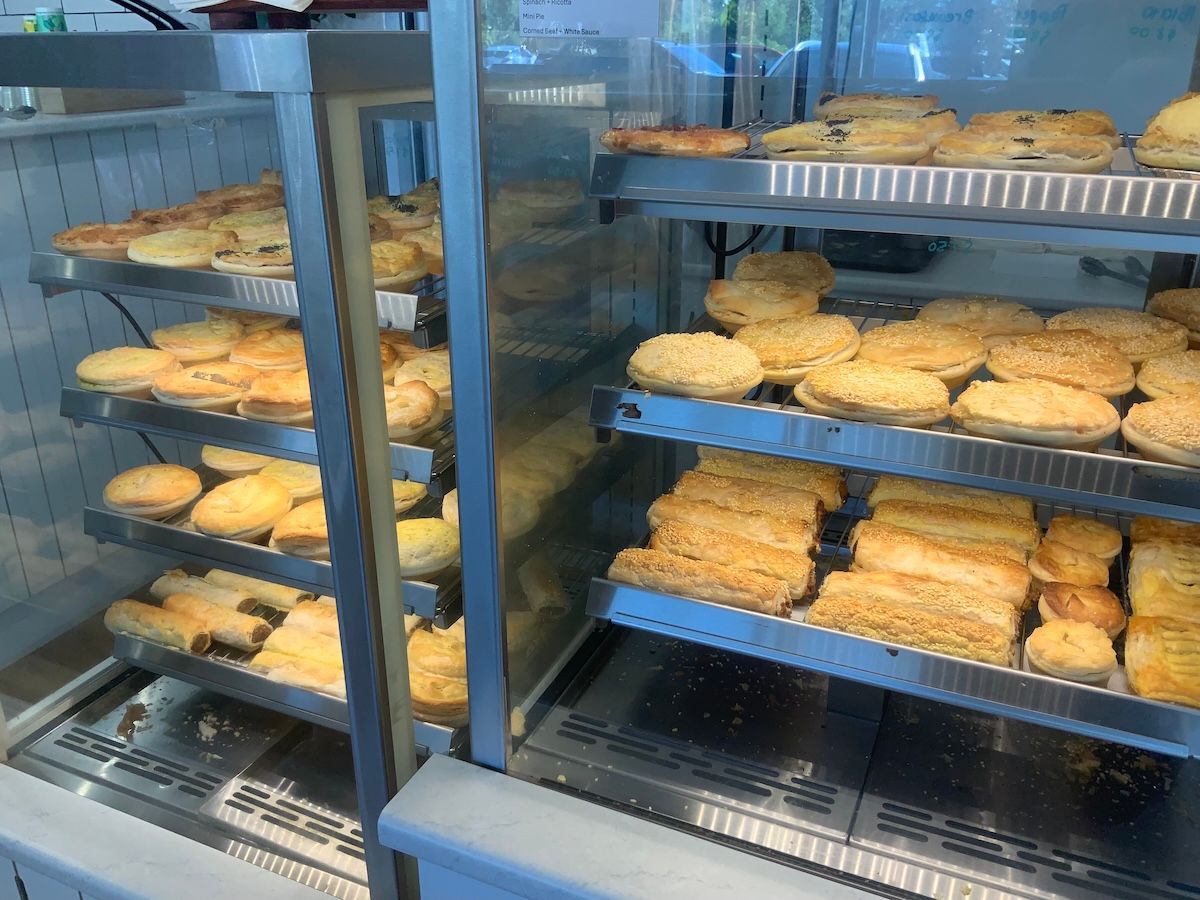 Bakery display cases filled with assorted pastries and bread loaves on metal racks — Cedar Park Bakehouse in Taranganba, QLD
