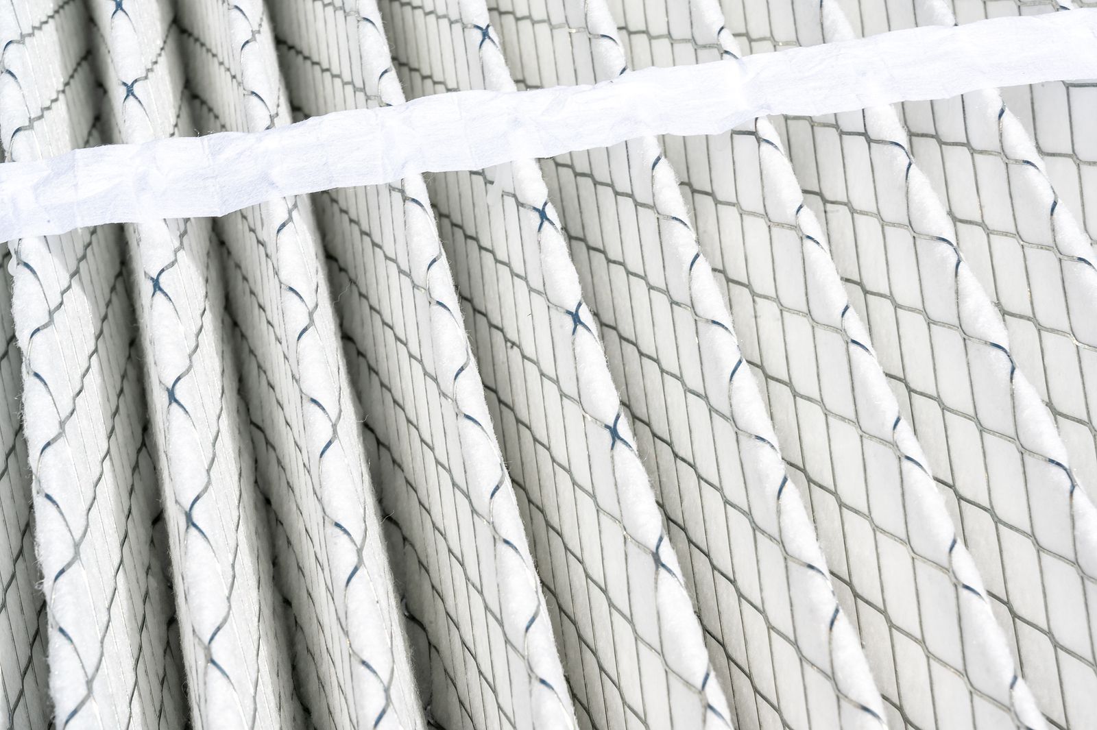 Close-up of a pleated air filter with a grid-like pattern and a white paper band across the top.