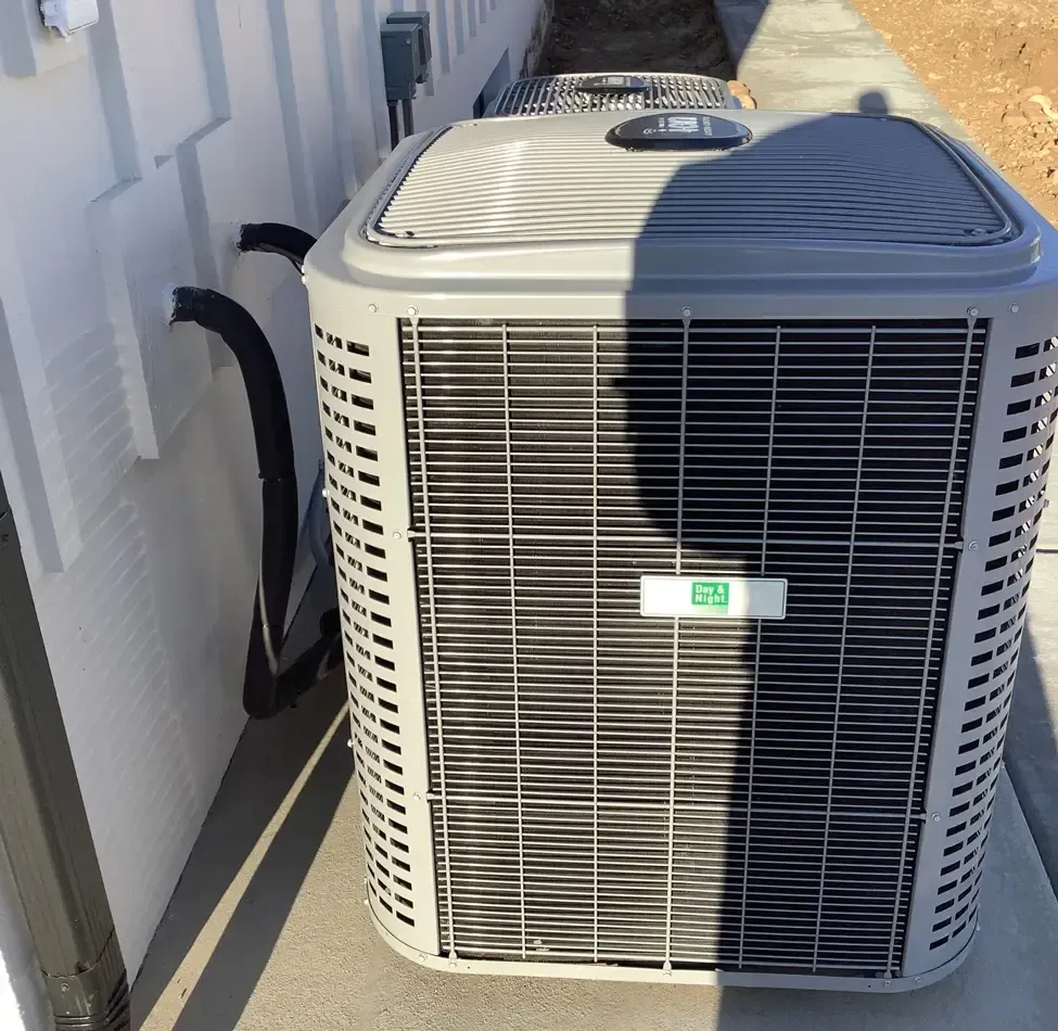 Technician kneeling beside an outdoor HVAC unit, inspecting it with tools near a building wall. Technician kneeling beside an outdoor HVAC unit, inspecting it with tools near a building wall.