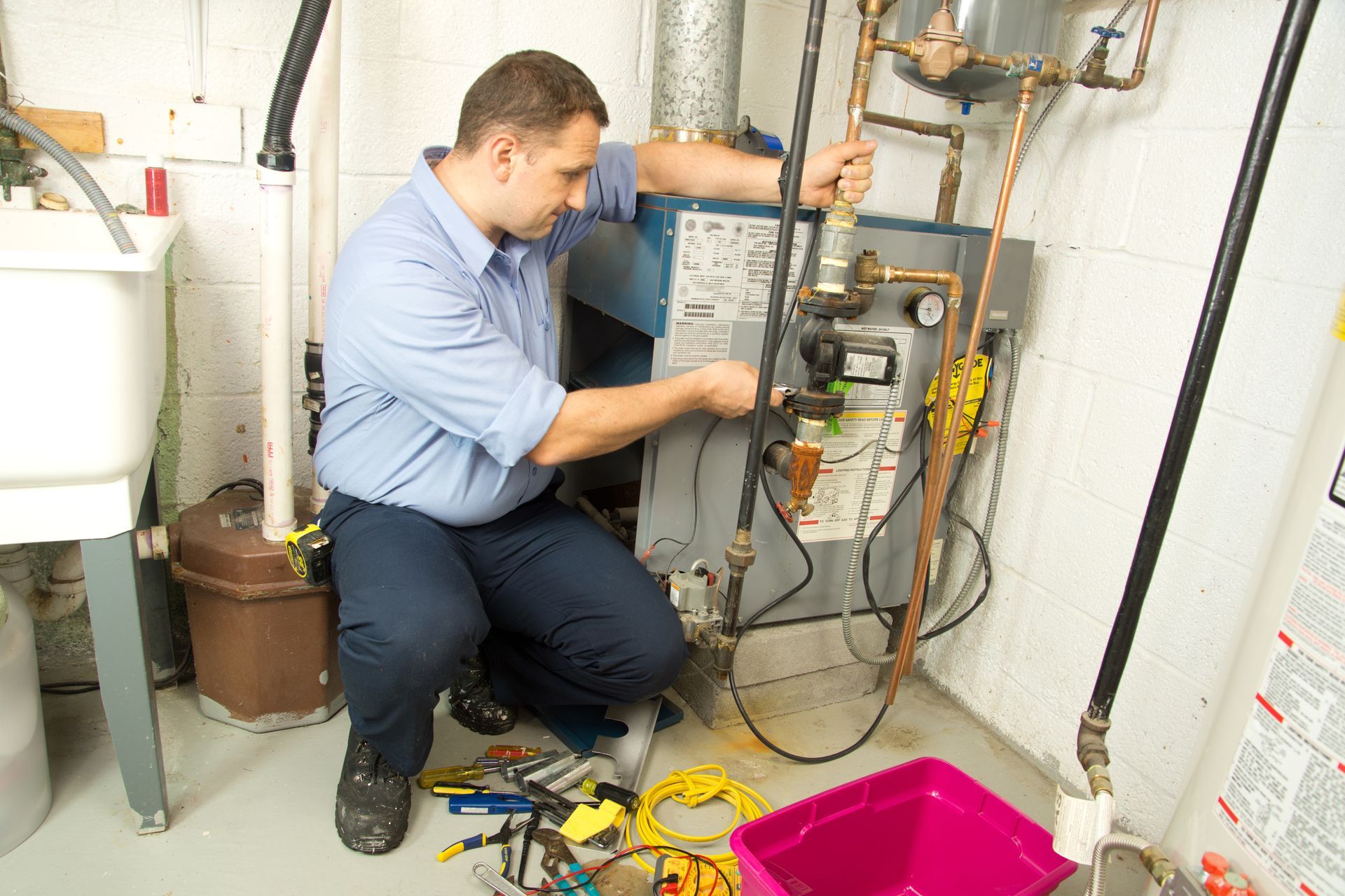 Technician inspecting a wall-mounted furnace with tools in a utility room Technician inspecting a wall-mounted furnace with tools in a utility room