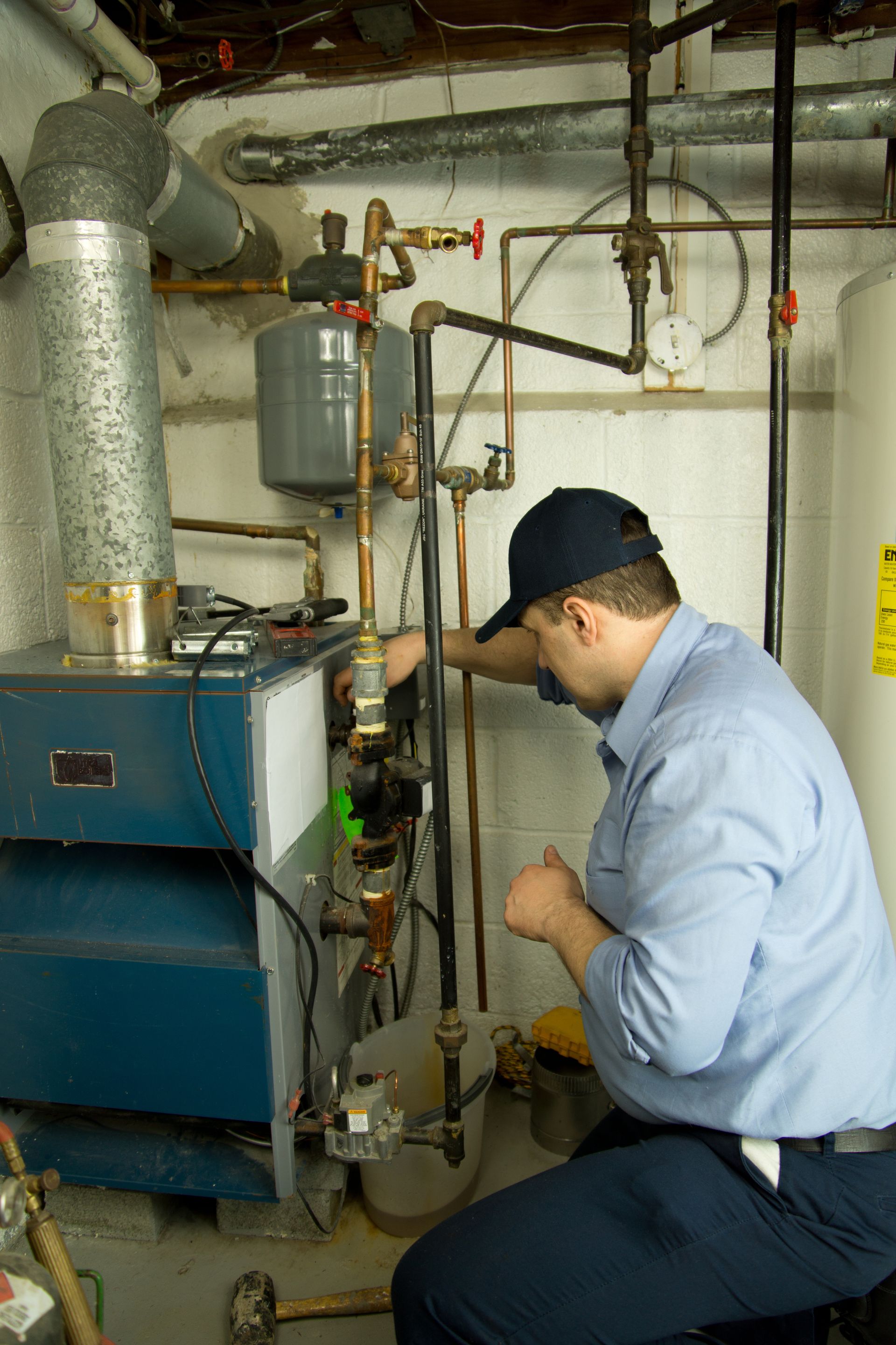 Technician inspecting a boiler and pipes in a basement utility room Technician inspecting a boiler and pipes in a basement utility room