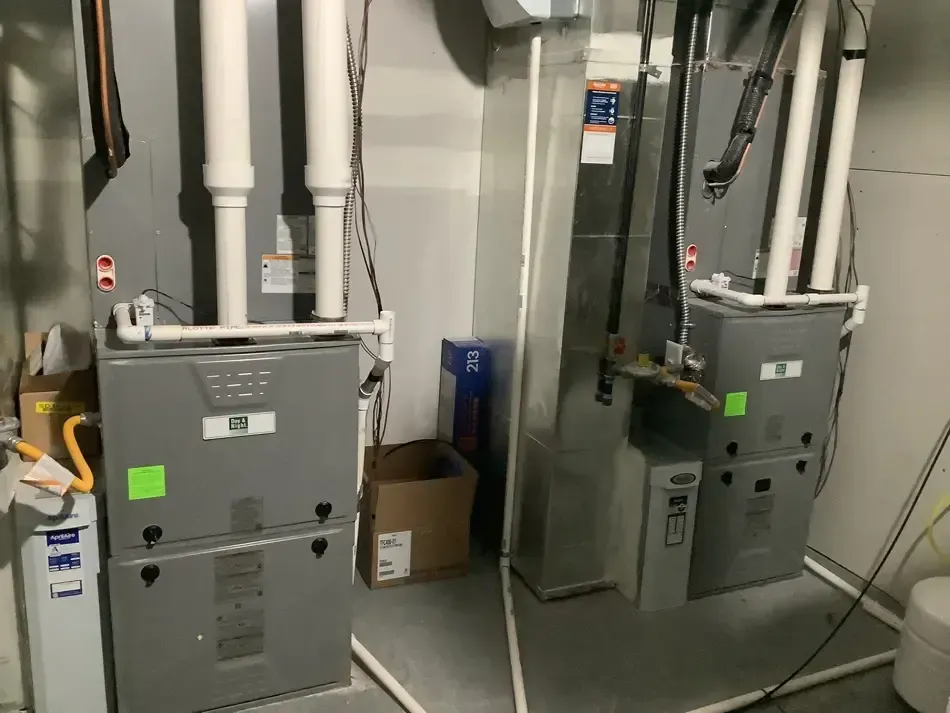 Technician installing a white wall-mounted boiler in a basement utility room Technician installing a white wall-mounted boiler in a basement utility room