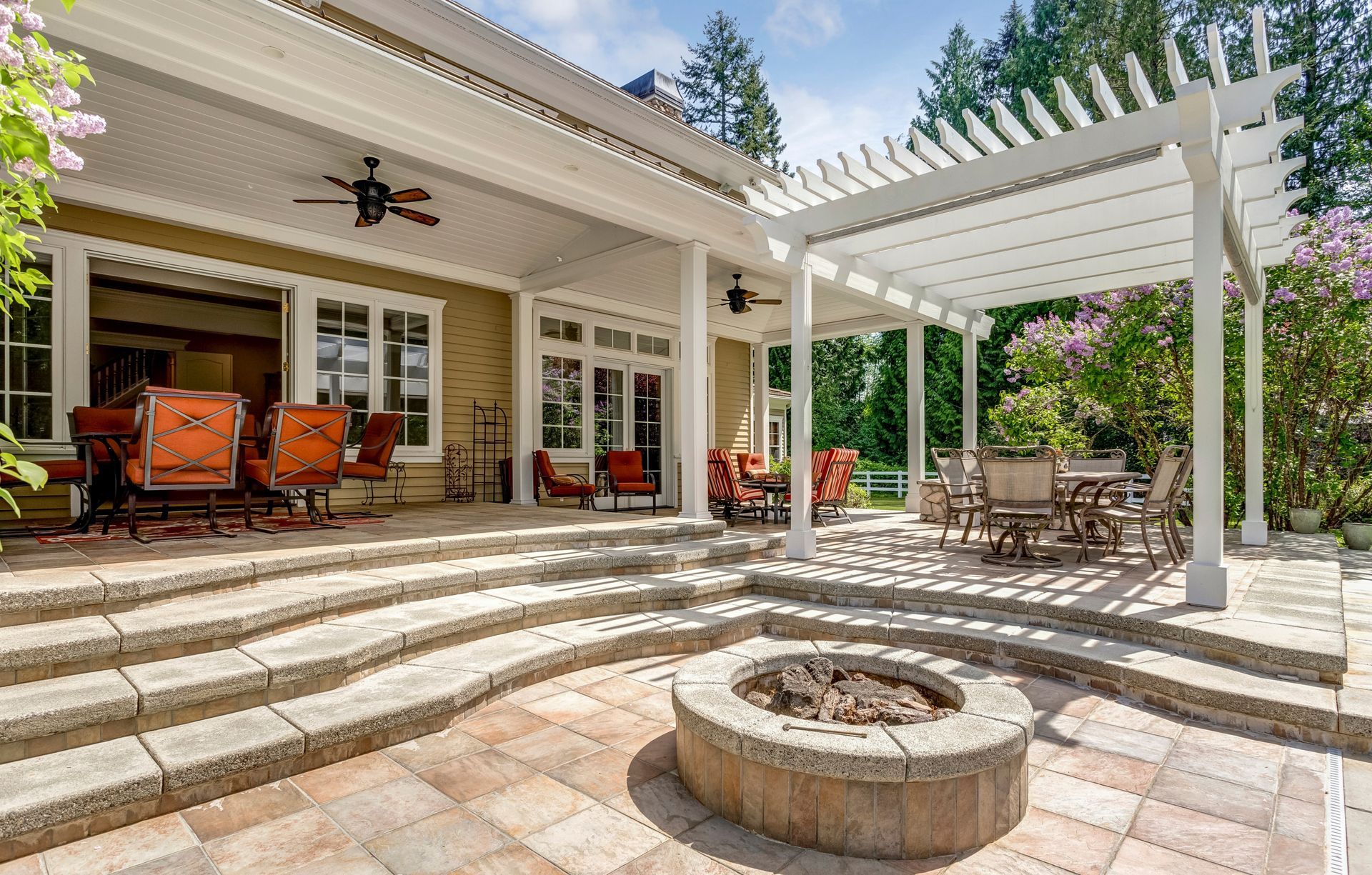 Back patio with fire pit, pergola, seating areas, and steps leading to the house.