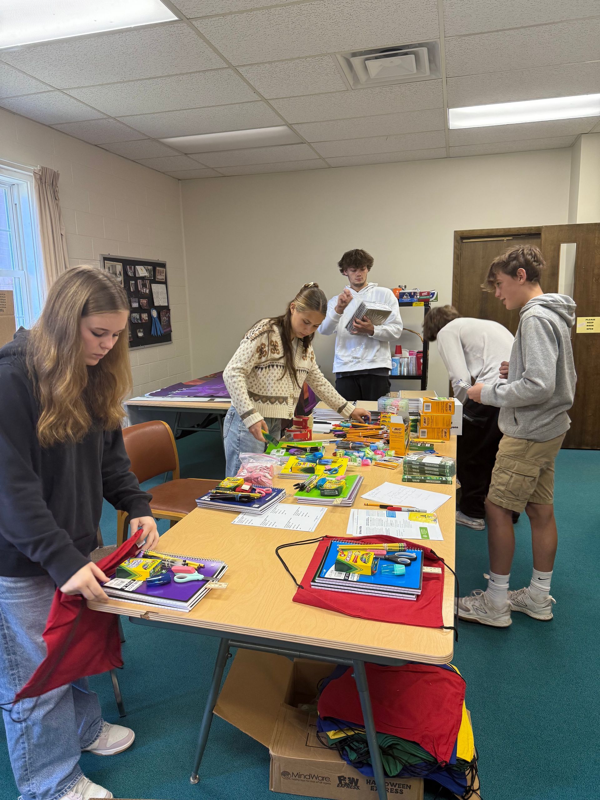 People browsing a colorful craft table in a classroom or community room