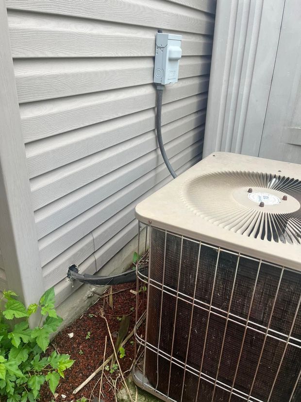 Outdoor air conditioner unit beside gray house siding and an electrical box with conduit nearby.