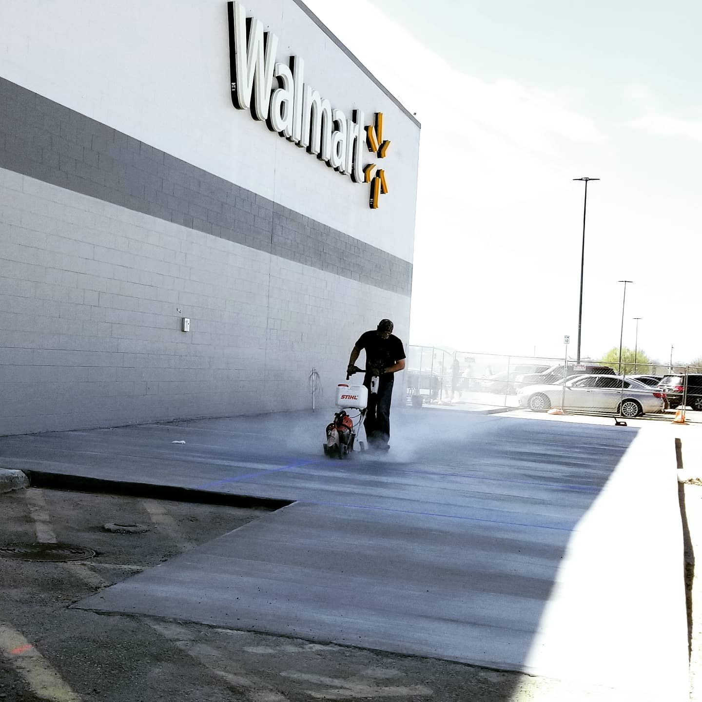 Walmart storefront with a person pushing a shopping cart across the parking lot