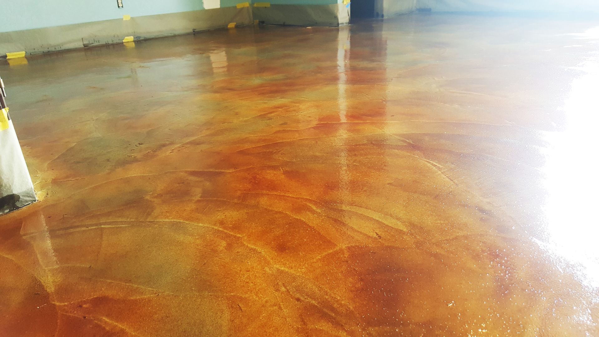 Polished reddish-brown concrete floor in an empty indoor space with bright light reflections