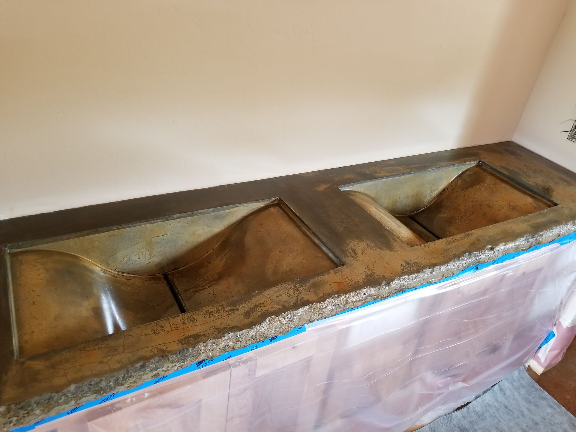 Built-in countertop sink with three basins and blue-tiled trim against a wall.