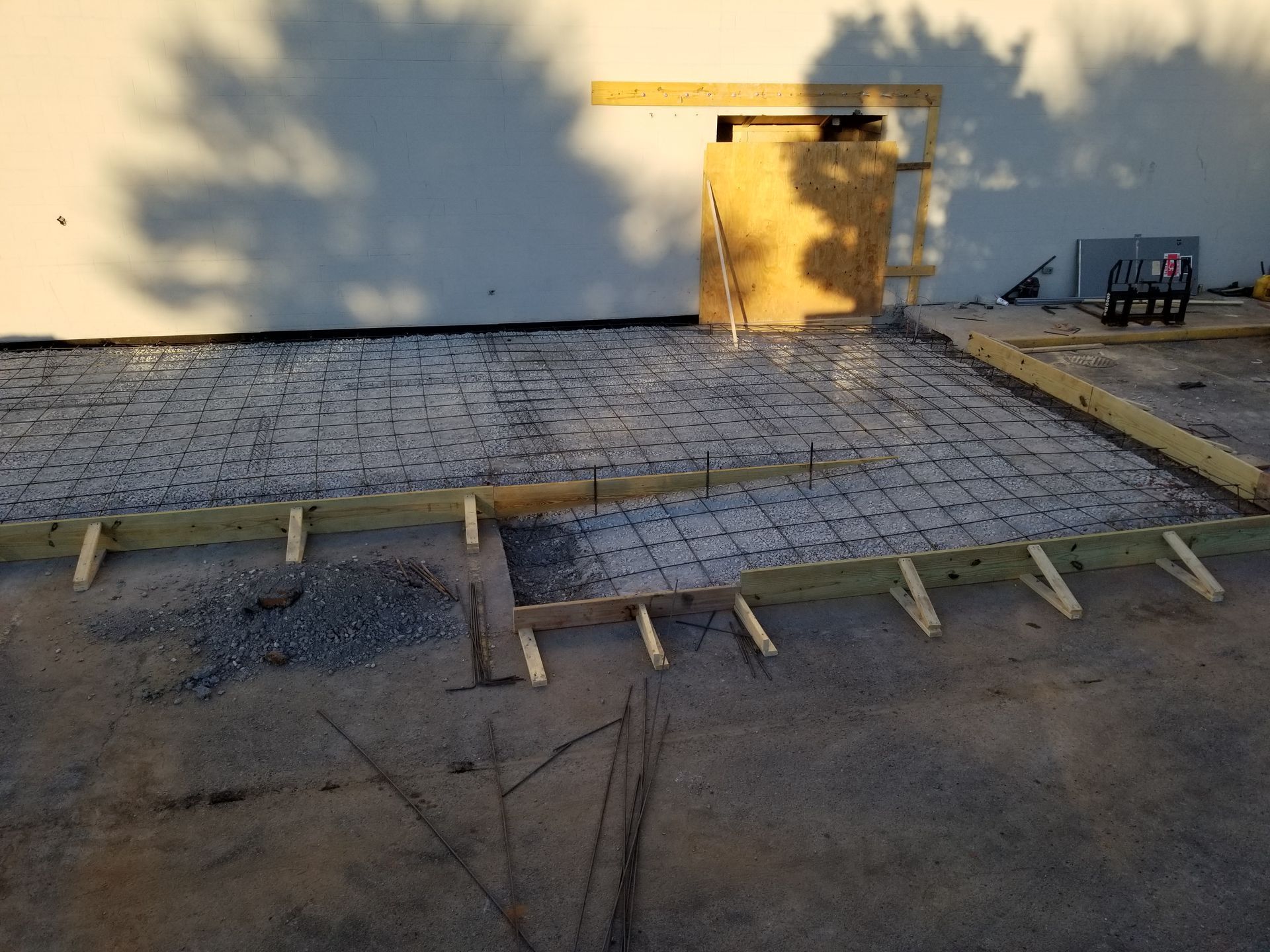 Outdoor rooftop with yellow wall, solar panels, and wooden framing on gravel surface.