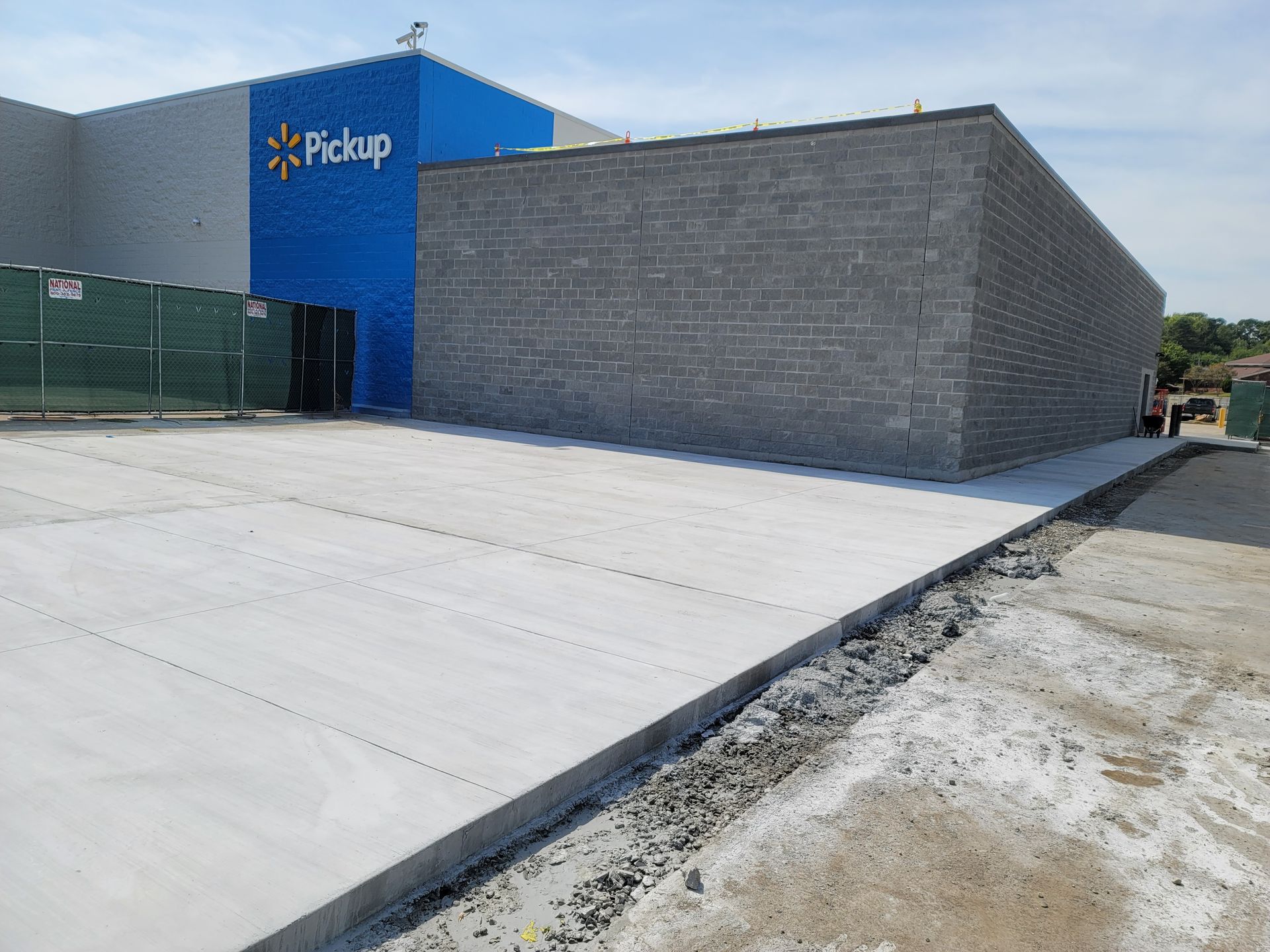 Blue pickup building exterior with large concrete loading area and gray brick wall