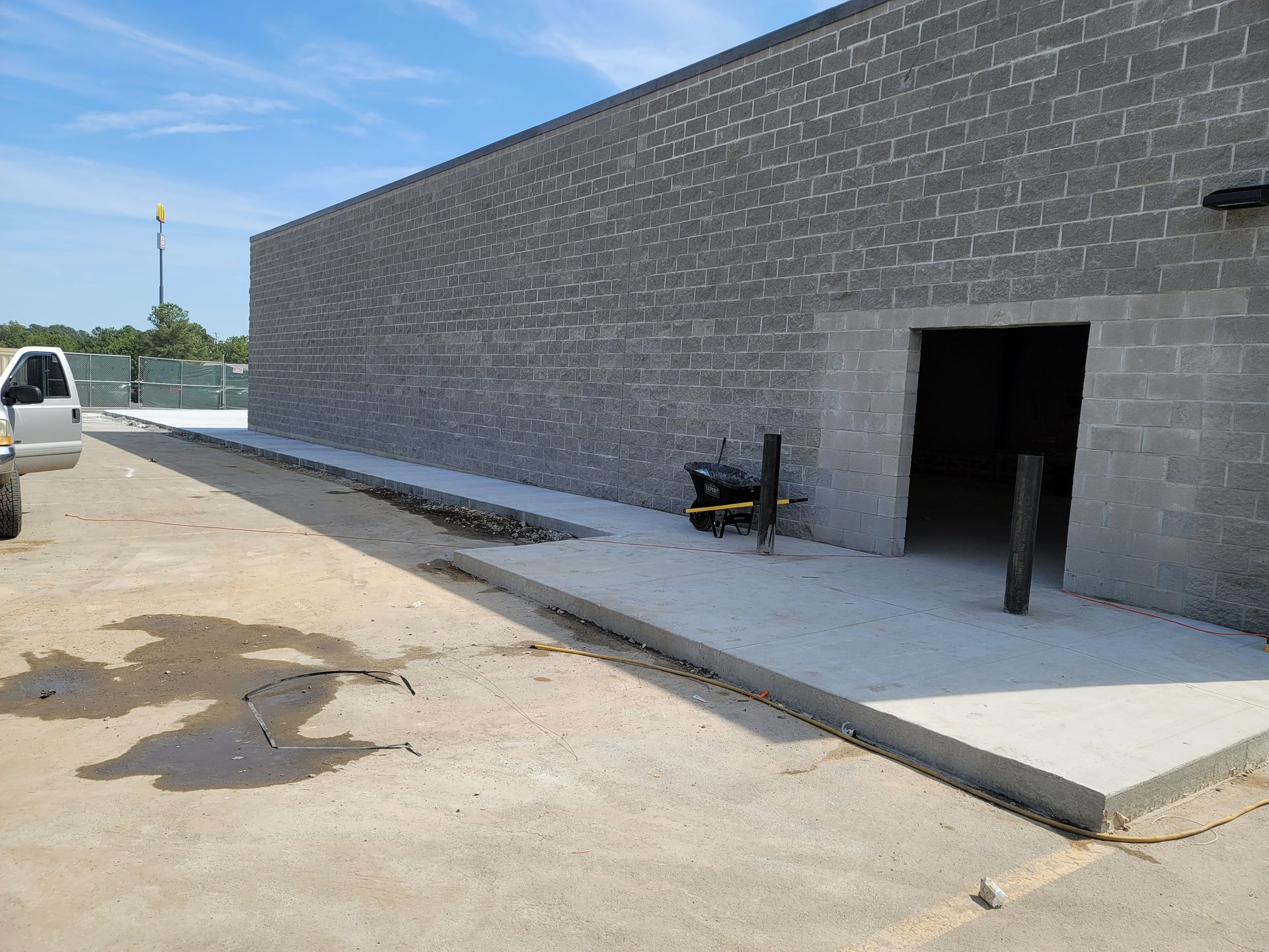 Concrete ramp beside a gray brick building, leading to a dark doorway on a construction site