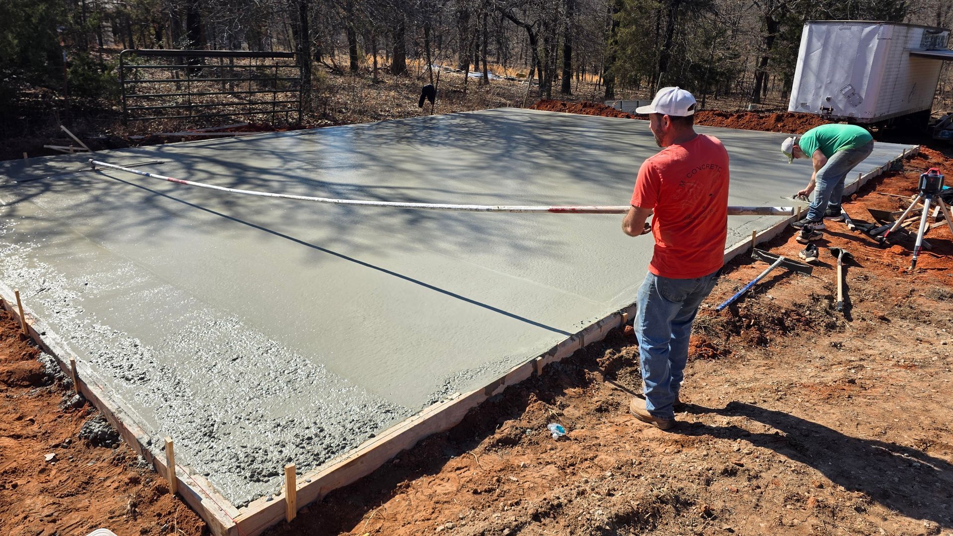 Workers smoothing fresh concrete slab at a construction site outdoors