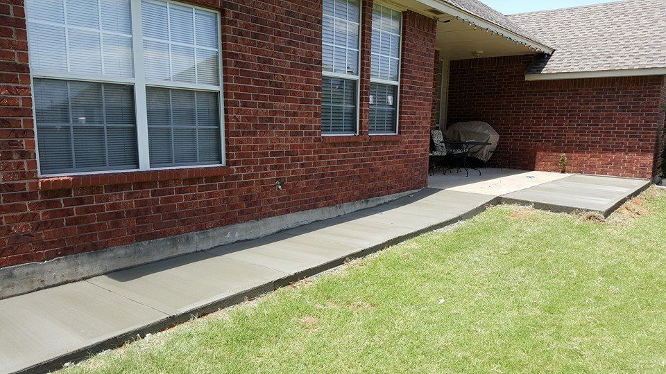 Brick house exterior with a concrete accessibility ramp along the lawn and covered porch.