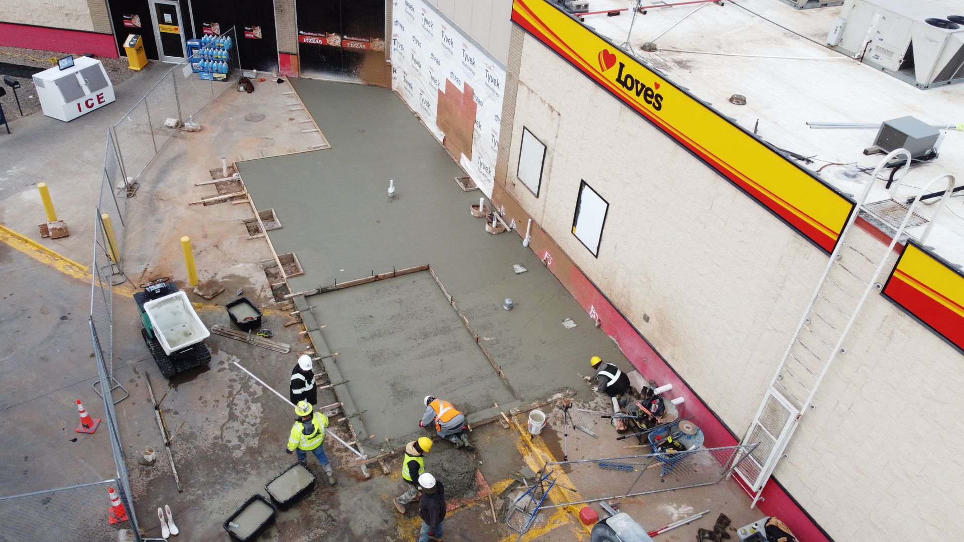 High-angle view of workers clearing debris outside a store with a yellow and red sign