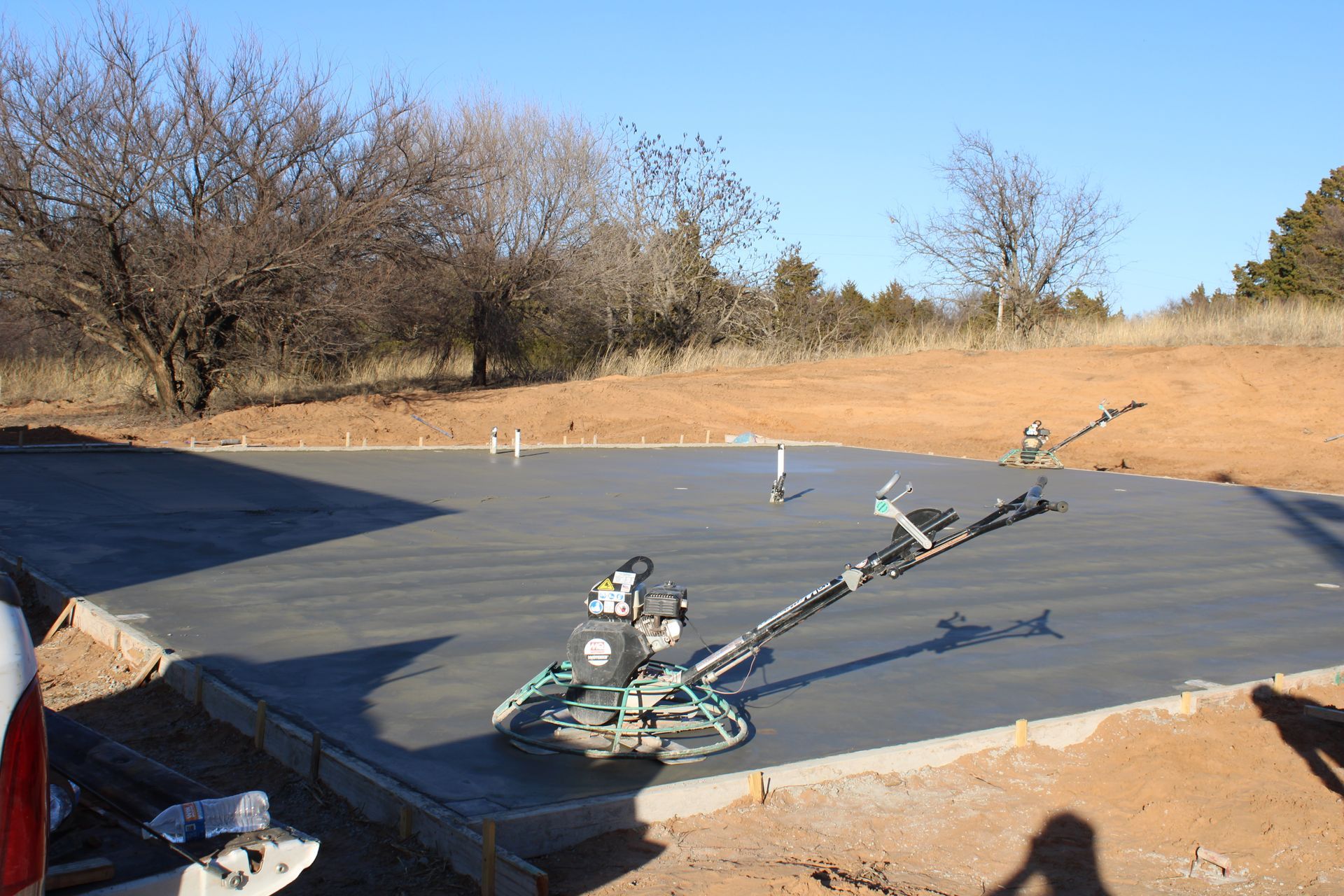 Small robot on a black tarp in a dry field with trees in the background