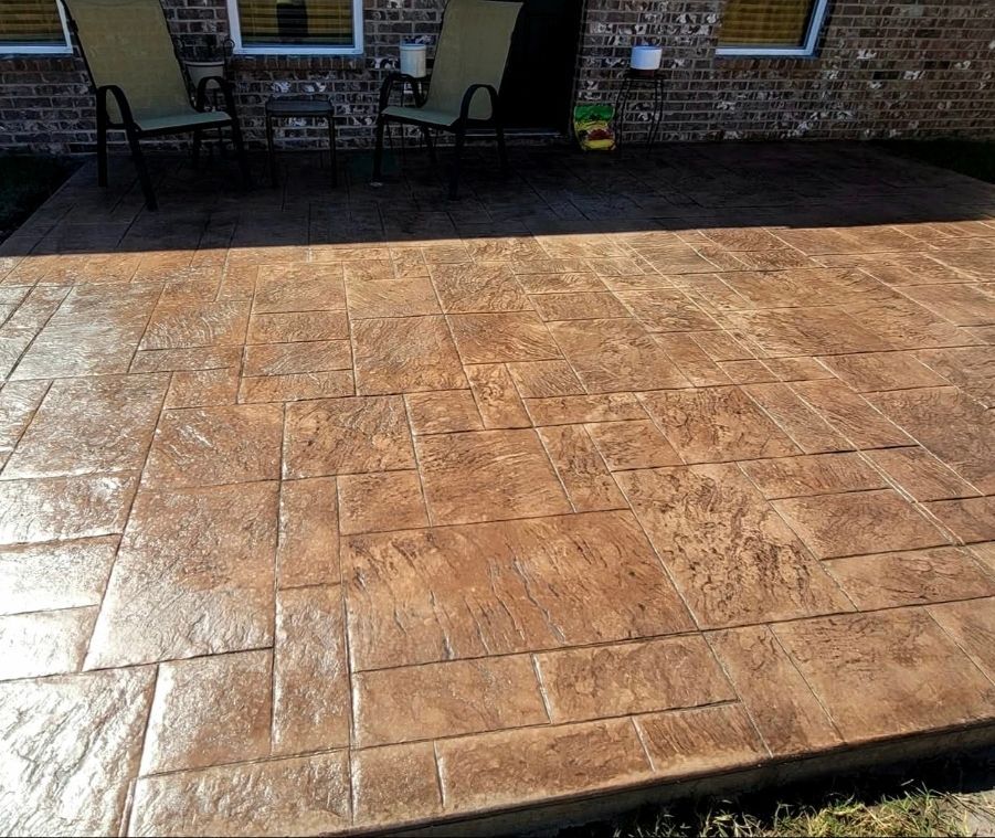 Sunlit tan tiled patio in front of a brick house with outdoor chairs and table in shade