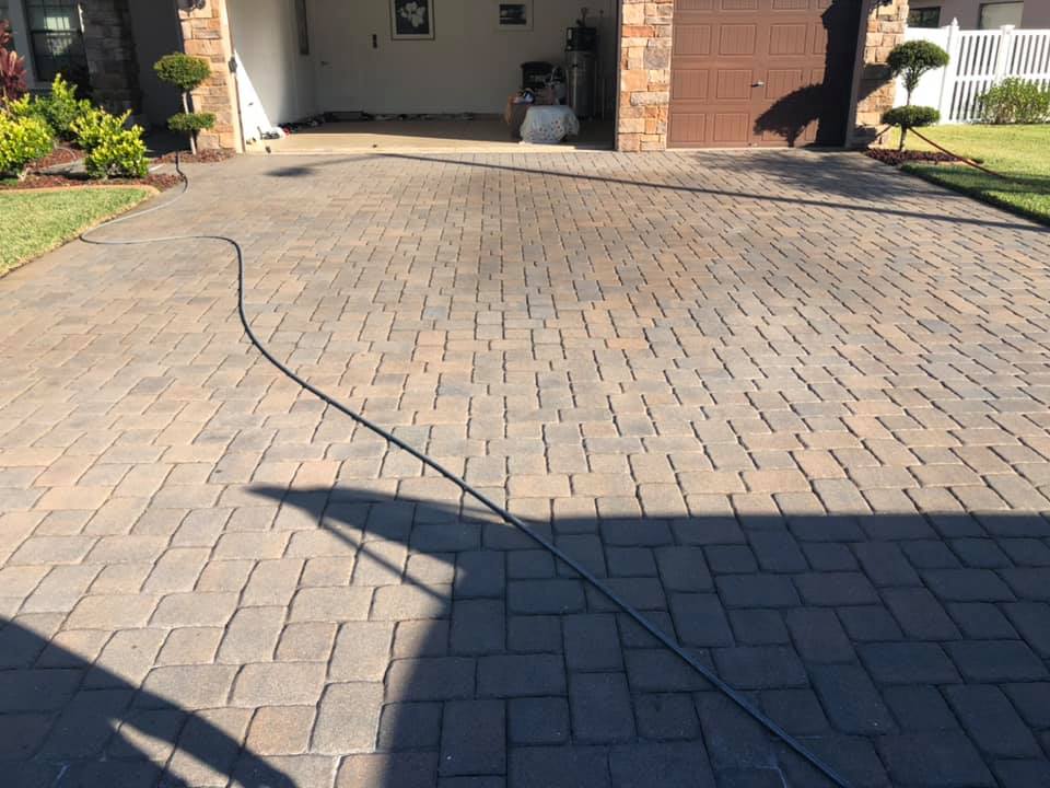 Brick driveway with a dark hose running across it, leading to a garage.