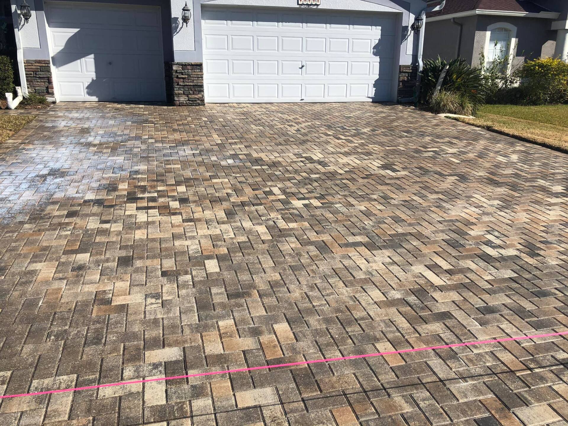 Brick paver driveway in front of a garage, with a house in the background.