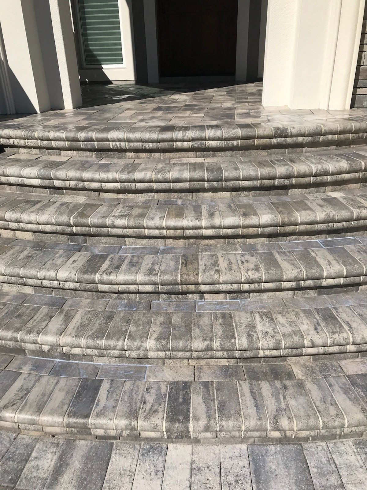 Gray brick steps leading to a doorway with a white column on either side.