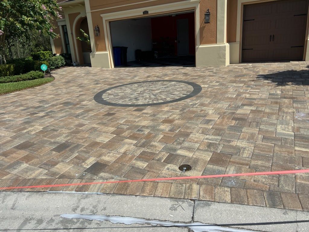 Brick driveway with a circular design in front of a garage.