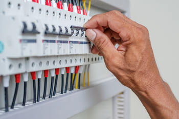 A close up of a person 's hand working on an electrical box.